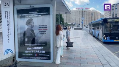 Окачиха плакати пред френското посолство в Москва, призоваващи военните им да се предадат