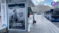 Окачиха плакати пред френското посолство в Москва, призоваващи военните им да се предадат